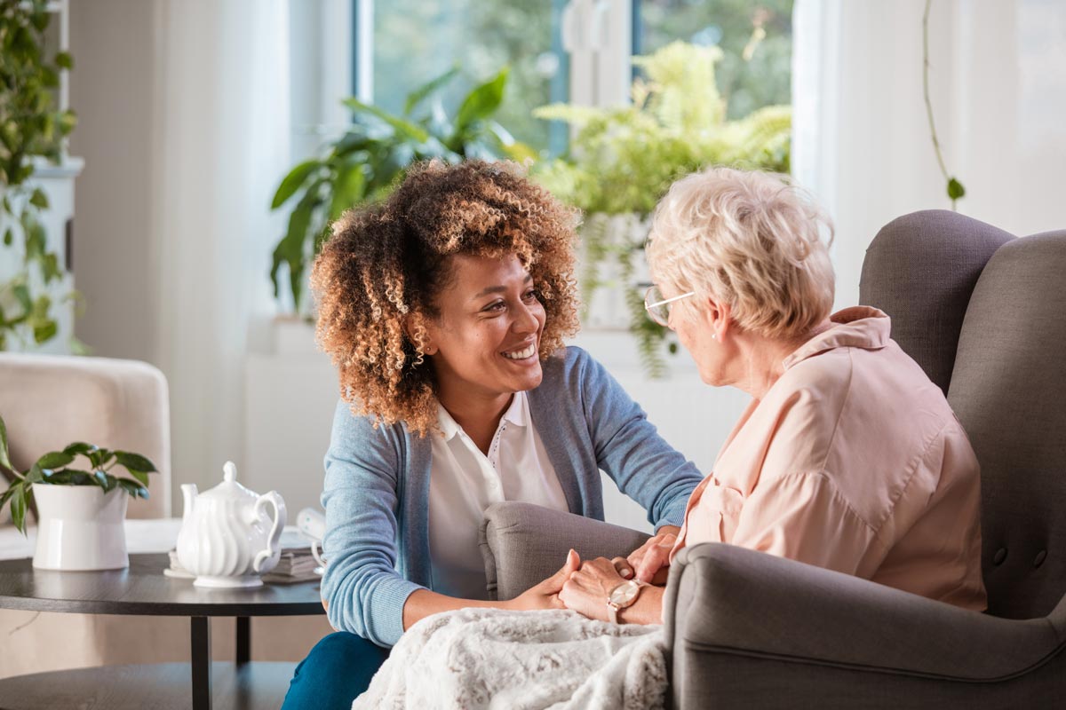 woman taking care of a senior citizen in a living room